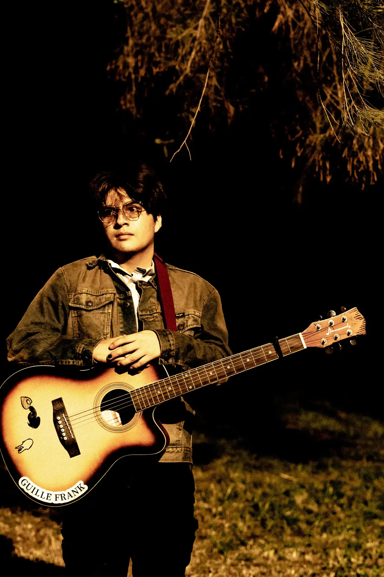 Retrato nocturno de Guille Frank con chamarra de mezclilla y guitarra
